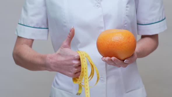 Nutritionist Doctor Healthy Lifestyle Concept - Holding Organic Grapefruit Fruit and Measuring Tape