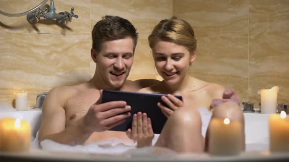 Happy Couple Watching Movie on Tablet Pc During Bathing, Romantic Time Together