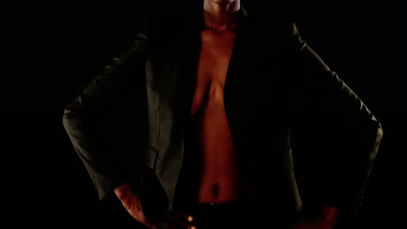 Androgynous man in blazer posing against black background