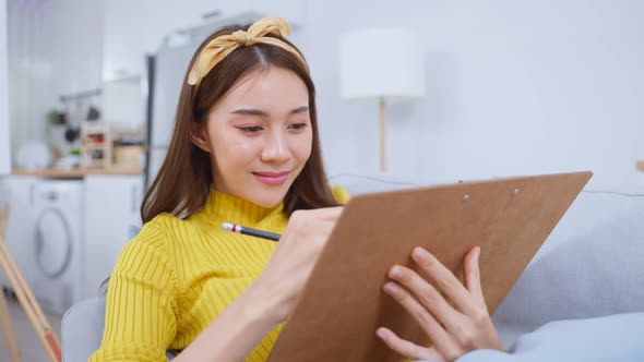 Asian woman artist drawing picture on painting board in living room.