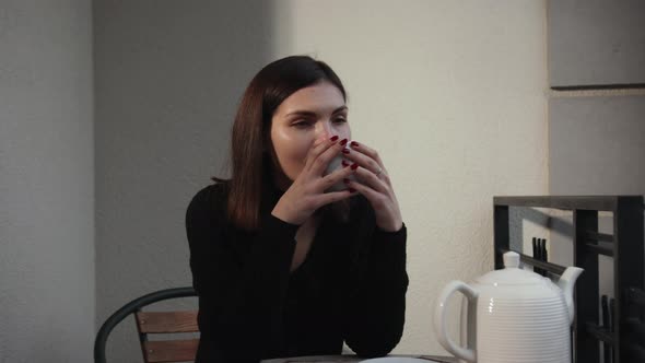 Young Beautiful Woman Sitting Home in Chair By Window with Cup of Hot Coffee