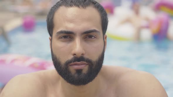 Close-up Face of Bearded Middle Eastern Man with Brown Eyes and Black Hair Looking at Camera and