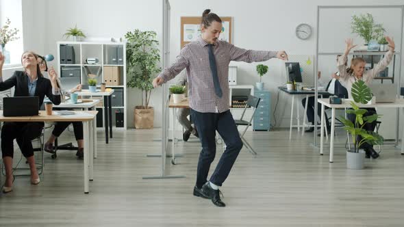 Creative Guy Performing Modern Dance in Office While Employees Having Fun in Background
