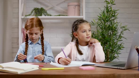 Two Little Children Girl Have Video Call with Teacher Using Laptop for Studying Online.