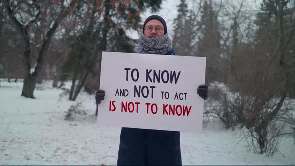 Male Protester Holding A Sign in the park To know and not to act is not to know