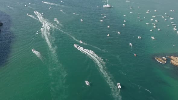 Tracking aerial: Several boats round a point in green Knysna Lagoon
