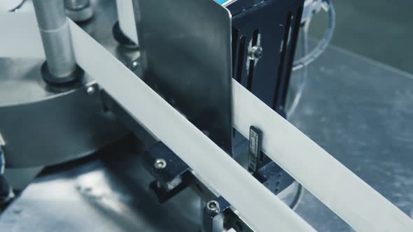 Handheld tracking shot of glass medicine bottles containing liquid moving along conveyor belt while