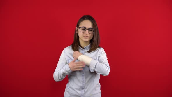 A Young Woman Wearing Glasses Hurts Her Arm and Touches Her Sore Arm