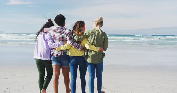 Happy group of diverse female friends having fun, walking along beach