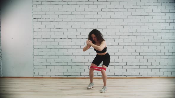 Workout in Sports Studio  Young Woman with Curly Hair Training with an Elastic Band