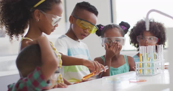 Video of happy african american pupils doing experiment during chemistry lesson