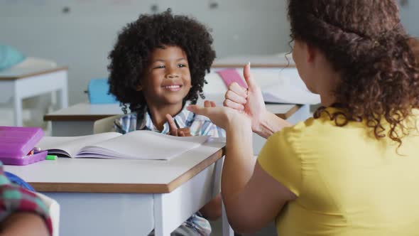 Video of happy caucasian female teacher learning math to african american boy