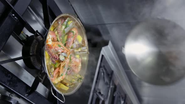 The Chef Removes the Lid From the Cataplan Which Cooks Seafood and Vegetables on a Gas Stove