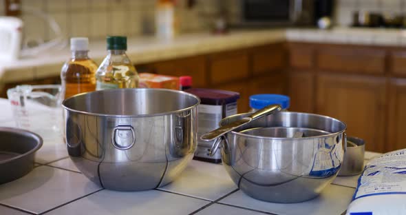 Mixing bowls, utensils and ingredients prepared for baking a vegan chocolate cake on a kitchen count