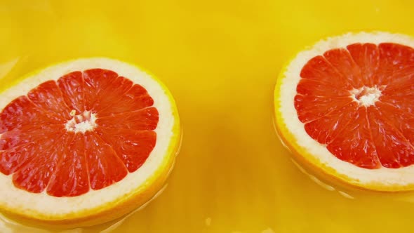 Rotating segments of ripe and juicy grapefruit on an orange background. Slow motion.