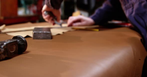 Shoemaker cutting a piece of leather