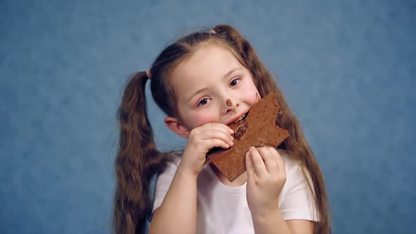 Young girl eating chocolate bar. Happy cutegirl isolated over background eating chocolate