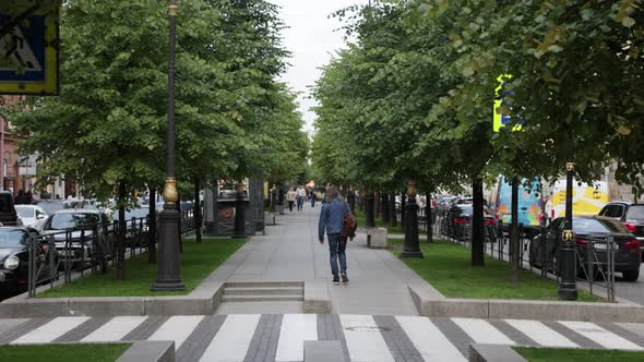 People Walk Along the Alley a Beautiful Street in the City with Green Trees Pedestrians Walking