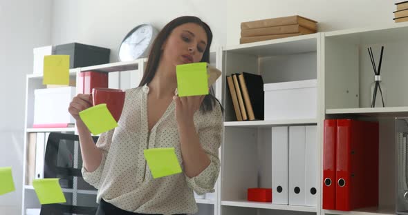 Businesswoman in White Blouse Considering Stickers on Glass and Talking on Phone