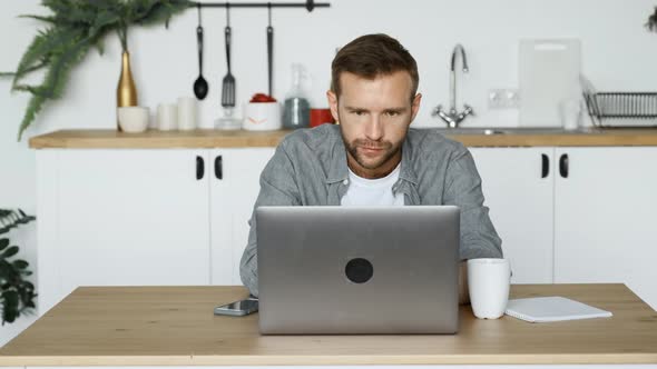 A Young Thoughtful Freelance Man Looking at A Monitor Screen, Working at a Computer