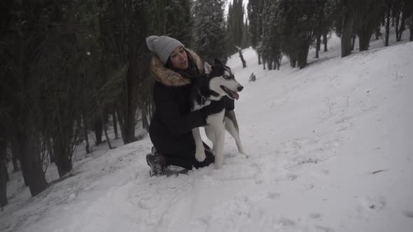 Woman hugging dog in winter forest