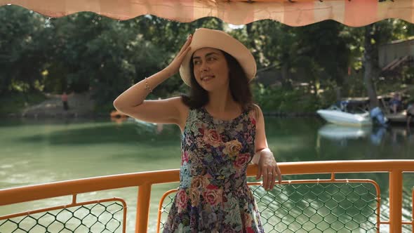 Elegant happy young woman in a straw hat and dress stands and sightseening