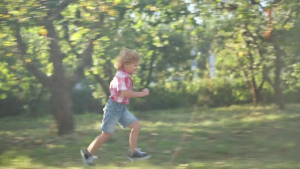 Side View Joyful Redhead Little Boy Running in Sunshine in Spring Summer Park Having Fun