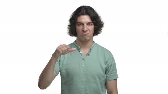 Image of Attractive Hispanic Guy with Long Dark Hair Wearing Green Shirt Grimacing Displeased and