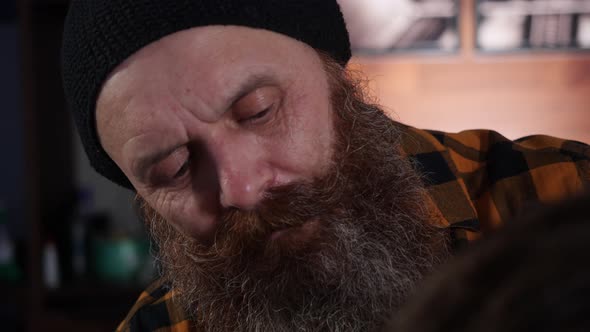 Adult Male Barber in Plaid Shirt Does Haircut To a Guy's Client in Barbershop