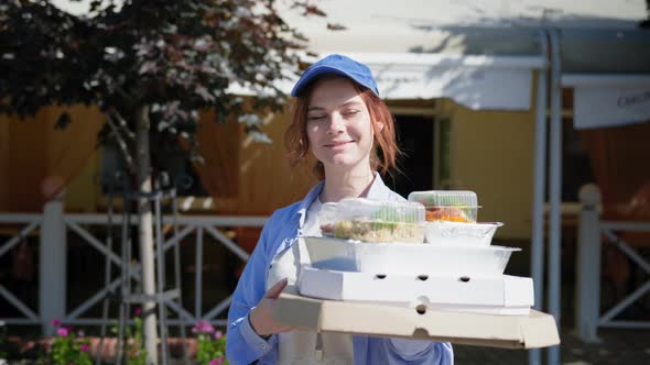 Girl Working in Delivery Service Holds an Order of Food in Cafe or Online Store with Home Delivery