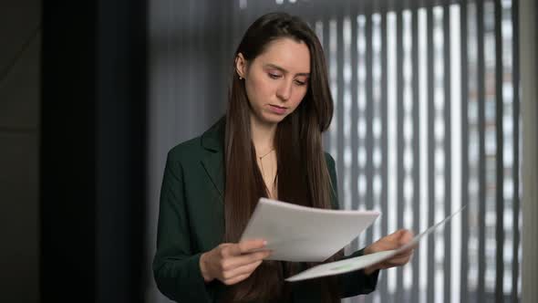 Young woman is studying documents, looking at them in the office