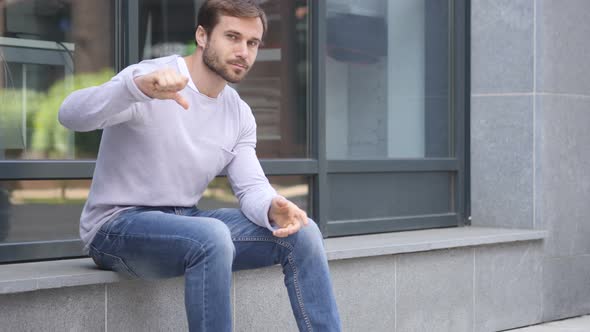 Thumbs Down by Handsome Man Sitting Outside Office Window