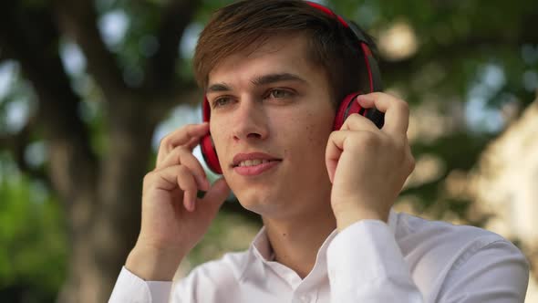 Headshot Portrait Happy Smiling Young Man in Headphones Singing Dancing Listening to Music Outdoors