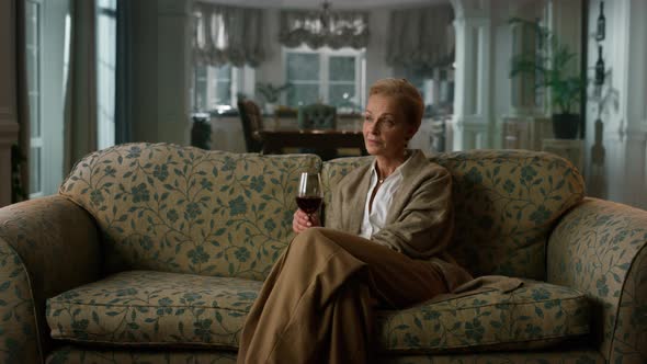 Rich Senior Woman Drinking Red Wine in Luxury Apartment