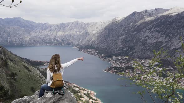 A Girl with a Backpack Sits on Top of a Mountain in Montenegro