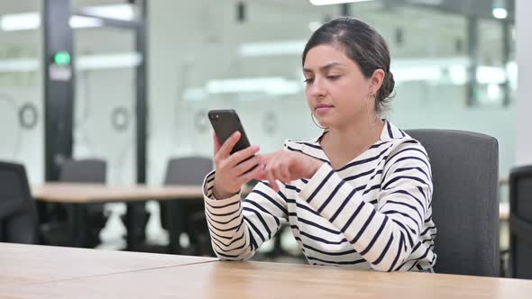 Serious Indian Woman Using Smartphone in Office 