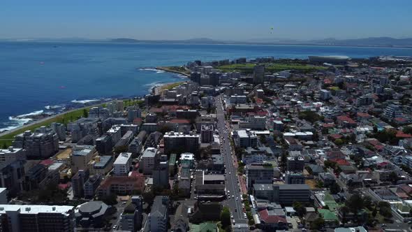 Drone shot of Sea Point, Cape Town - drone is reversing, watching paragliders coming down from Signa