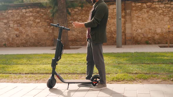 Tourist Man Take Electric Kick Scooter or Bike Bicycle in Sharing Parking Lot Tourist Phone