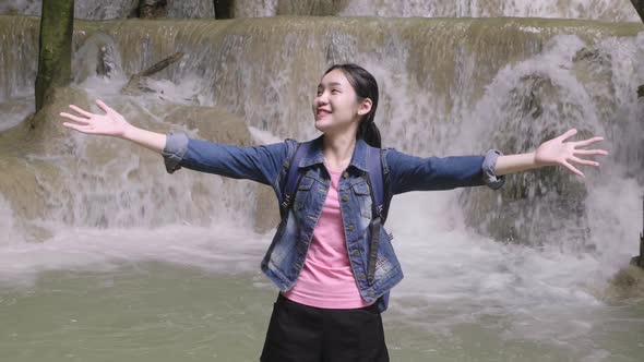 Young Asian Woman Raised Hands At Waterfall