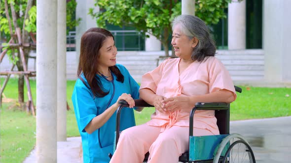 Asian careful caregiver or nurse taking care of the patient in a wheelchair.  Concept of happy retir