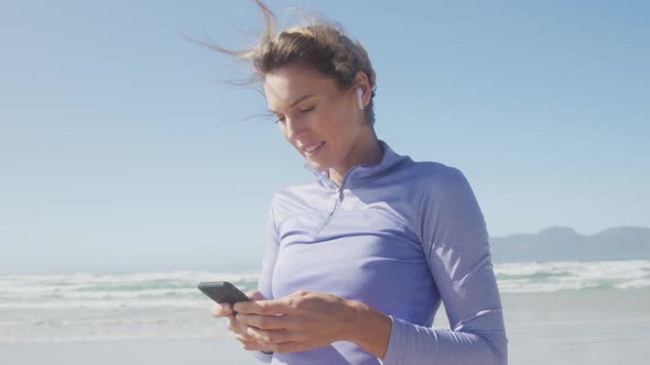 Athletic woman listening music on the beach