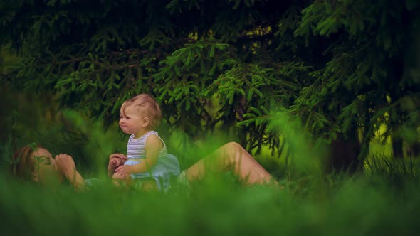 Mom with a child have fun lying in a park under a tree.