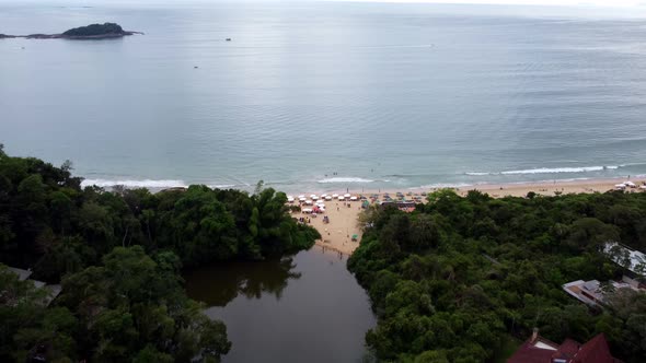 Aerial flying over the beach and the river of Ubatuba on sunny day, Brazil