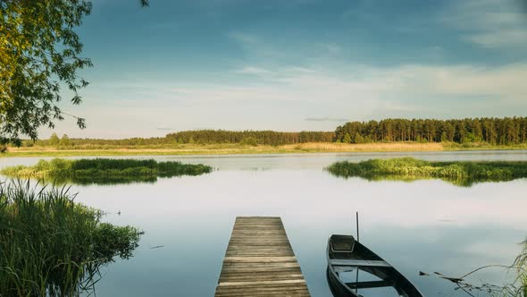 Belarus Lake Or River And Old Wooden Rowing Fishing Boat Near Old Wooden Pier In Beautiful Summer