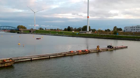 Drone pulls from cloud covered windmills on the shore next to the river Schelde