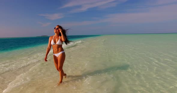 Young happy lady on photoshoot spending quality time at the beach on sunny blue and white sand backg