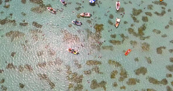 Aerial view of boats and people swimming in turquoise sea of Rio do Fogo, Brazil