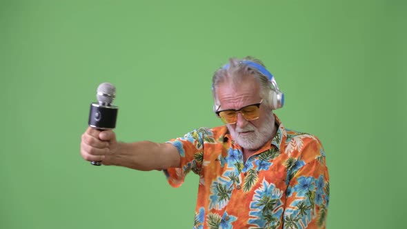 Handsome Senior Bearded Tourist Man Ready for Vacation Against Green Background