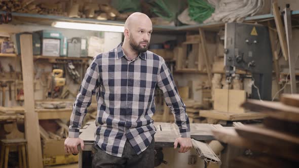 A Brutal and Bald Man in a Carpentry Workshop