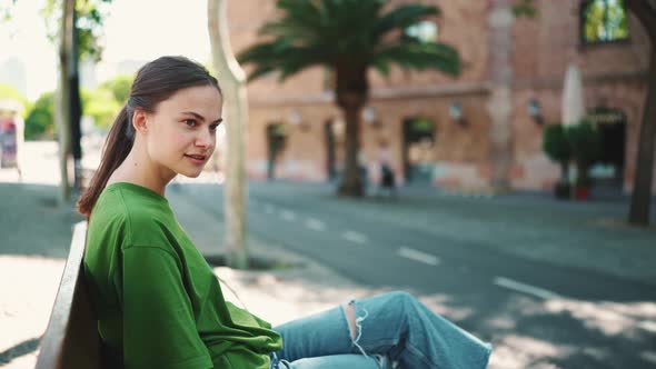 Handsome blonde woman wearing green t-shirt sitting on the bench